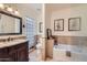 Bright bathroom with dark wood vanity, glass block window, and separate tub at 6314 N 14Th Pl, Phoenix, AZ 85014