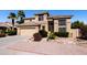 Attractive tan two-story home with well-manicured landscaping, rock features, and a two car garage at 696 W Del Rio St, Gilbert, AZ 85233