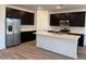 Modern kitchen features stainless steel appliances, dark cabinetry and white countertops at 7694 W Saddlehorn Rd, Peoria, AZ 85383