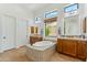 Bright bathroom featuring a soaking tub with tile surround, dual sinks, and many windows at 7915 E Stonecliff Cir, Mesa, AZ 85207