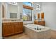 Bright bathroom showcasing a soaking tub with tile surround, dual sinks, and natural light at 7915 E Stonecliff Cir, Mesa, AZ 85207