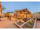 Entertainer's backyard featuring a built-in grill under a shaded pergola, desert landscaping, and a fire pit at 8541 E Canyon Estates Cir, Gold Canyon, AZ 85118