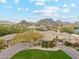 Estate aerial view with lush landscaping, a circular driveway, porte-cochere, pool, and a putting green at 9513 N 129Th Pl, Scottsdale, AZ 85259