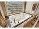 Bright bathroom featuring a large soaking tub with tile surround and window block for natural light at 9513 N 129Th Pl, Scottsdale, AZ 85259