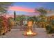Inviting outdoor seating area with a cozy fire pit, surrounded by lush landscaping and mature palms at 9513 N 129Th Pl, Scottsdale, AZ 85259