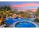 Inviting pool with rock waterfall and hot tub, set against a colorful sky and desert landscaping at 9513 N 129Th Pl, Scottsdale, AZ 85259