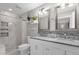 Bright bathroom featuring a marble-topped vanity, dual sinks, and a modern shower with decorative tile accents at 10602 N 35Th St, Phoenix, AZ 85028