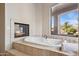 Luxurious soaking tub with fireplace and exterior views at 13126 E Turquoise Ave, Scottsdale, AZ 85259
