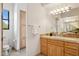 Light-filled bathroom with travertine counters, natural wood cabinets, and a toilet at 13126 E Turquoise Ave, Scottsdale, AZ 85259