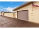 Home exterior featuring a tan garage door, house number, American flag, and a cracked driveway at 13311 W Copperstone Dr, Sun City West, AZ 85375