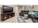 Open-concept living room with a large leather sectional, TV, and neutral tile flooring for modern comfort at 13311 W Copperstone Dr, Sun City West, AZ 85375