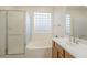 Well-lit bathroom with a tub, glass-enclosed shower, and vanity with a sink at 18624 E Cattle Dr, Queen Creek, AZ 85142