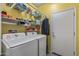 Bright laundry room has a side by side washer and dryer, shelving and yellow walls at 19232 W Madison St, Buckeye, AZ 85326