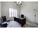A bright home office with plantation shutters, a ceiling fan, and a spacious work desk at 19746 N Heron Ct, Maricopa, AZ 85138
