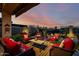 Inviting covered patio with cozy wicker furniture, stylish striped rug, and a romantic fire pit at sunset at 2124 N 89Th Pl, Mesa, AZ 85207