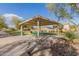 Inviting picnic area with covered ramada, seating, lush foliage, and convenient walking path at 24207 W Desert Bloom St, Buckeye, AZ 85326
