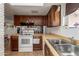 Practical kitchen setup with white appliances, wooden cabinets, and a double sink for convenience at 306 N Winthrop Cir, Mesa, AZ 85213