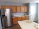 Open kitchen featuring wood cabinets, stainless steel refrigerator, and an island, perfect for entertaining and meal preparation at 39837 N Manetti St, San Tan Valley, AZ 85140