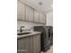 Modern laundry room with front load washer and dryer, granite counters and custom cabinets at 40198 N 105Th Pl, Scottsdale, AZ 85262