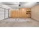 Garage with built in shelves along the back wall next to an open garage door at 41848 W Michaels Dr, Maricopa, AZ 85138