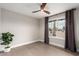 Inviting bedroom featuring light hardwood floors, a ceiling fan, and a large window with curtains at 5561 W Greenbriar Dr, Glendale, AZ 85308
