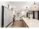 Bright kitchen features white cabinets, herringbone backsplash, stainless appliances, island seating and modern pendants at 5561 W Greenbriar Dr, Glendale, AZ 85308