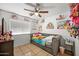 Cozy bedroom features a ceiling fan and daybed with shelves displaying an array of dolls and figurines at 6922 S 26Th Ln, Phoenix, AZ 85041