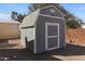 The storage shed has a gray painted exterior, and sits on gravel, nestled between a modular home and block wall at 7807 E Main St # Cc-98, Mesa, AZ 85207
