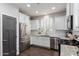 Bright kitchen with stainless steel appliances, white cabinetry, stone countertops, and stylish dark wood flooring at 10451 E Natal Ave, Mesa, AZ 85209