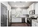 Bright kitchen with stainless steel appliances, white cabinetry, stone countertops, and stylish dark wood flooring at 10451 E Natal Ave, Mesa, AZ 85209