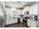 Well-lit kitchen featuring stainless steel appliances, white cabinets, and stone countertops with dark hardwood floors at 10451 E Natal Ave, Mesa, AZ 85209