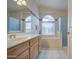 Bathroom featuring a dual-sink vanity, soaking tub with windows, and a separate glass-enclosed shower at 12450 W Holly St, Avondale, AZ 85392