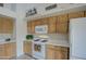 Well-lit kitchen with white appliances, wood cabinets, and tile flooring at 12450 W Holly St, Avondale, AZ 85392