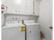 A well lit laundry room with a washer, dryer and white cabinets at 14013 N Boswell Blvd, Sun City, AZ 85351