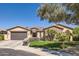 Charming single-story home featuring a stone facade, manicured landscaping, and a spacious driveway at 14870 W Aldea Cir, Litchfield Park, AZ 85340