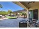 Covered patio featuring stone floors, a built-in grill area, pergola and manicured backyard with seating area and artificial turf at 14870 W Aldea Cir, Litchfield Park, AZ 85340