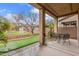 Charming back porch with an outdoor seating area, a manicured lawn, and lush greenery surrounding the backyard at 1562 W Lacewood Pl, Phoenix, AZ 85045