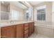 Bathroom with double sinks, modern fixtures, a large mirror, and a soaking tub beneath a window at 1562 W Lacewood Pl, Phoenix, AZ 85045