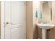 Powder room features a pedestal sink, framed mirror, and modern fixtures, adjacent to a white paneled door at 1562 W Lacewood Pl, Phoenix, AZ 85045