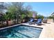 This backyard has a refreshing pool, lounge chairs, and a built-in grill with desert landscaping at 16935 W Cambridge Ave # 57, Goodyear, AZ 85395