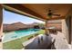 Inviting covered backyard patio with a dining table, ceiling fan, built-in grill, and a sparkling in-ground swimming pool at 1713 W Cottonwood Ln, Phoenix, AZ 85045
