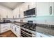 A modern kitchen features stainless steel appliances, granite countertops, and white cabinets at 1713 W Cottonwood Ln, Phoenix, AZ 85045