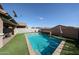 A backyard oasis featuring a stunning pool, lush grass, and umbrella-covered seating, offering a perfect retreat at 1713 W Cottonwood Ln, Phoenix, AZ 85045