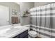 Bathroom with sink, toilet, decorative shelving, and a gray-and-white striped shower curtain at 17751 W Bloomfield Rd, Surprise, AZ 85388