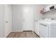 Functional laundry room with modern washer and dryer, ample shelving, wood-look flooring, and neutral paint at 17751 W Bloomfield Rd, Surprise, AZ 85388