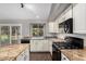 Kitchen with granite countertops, white cabinets, stainless sink, and black appliances overlooking the backyard at 20640 N 100Th Ln, Peoria, AZ 85382