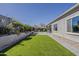 Green backyard with manicured artificial turf, mature landscaping, and convenient access to the patio at 21359 E Camacho Rd, Queen Creek, AZ 85142