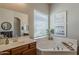 Bright bathroom featuring a soaking tub and a vanity with wood cabinetry and vessel sink at 21359 E Camacho Rd, Queen Creek, AZ 85142