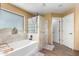 Bathtub with glass-block window and tiled shower in a neutral color palette at 224 N 236Th Ave, Buckeye, AZ 85396