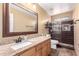 Bathroom with granite countertop, wood cabinets, decorative mirror and tiled shower at 224 N 236Th Ave, Buckeye, AZ 85396